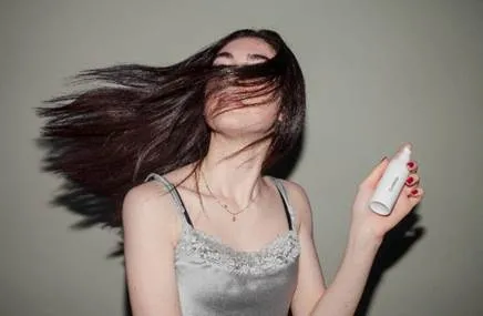 A model with dark hair posing for a serum ad