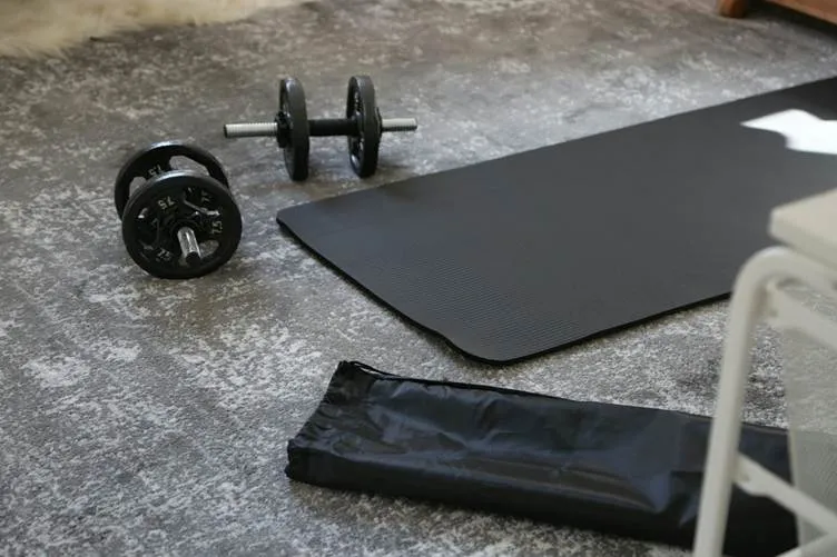 a pair of dumbbells and a black mat on the floor